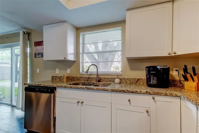 a kitchen with granite countertop cabinets sink and window