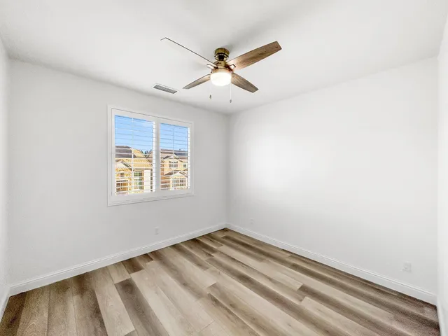 an empty room with ceiling fan and windows