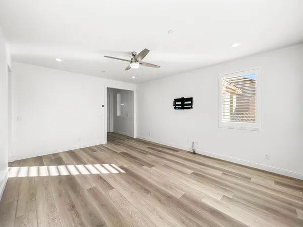a view of an empty room with wooden floor and a window