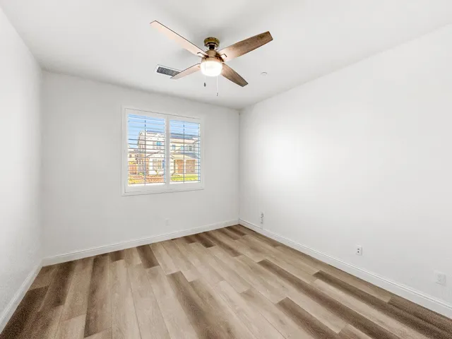 an empty room with a ceiling fan and a window