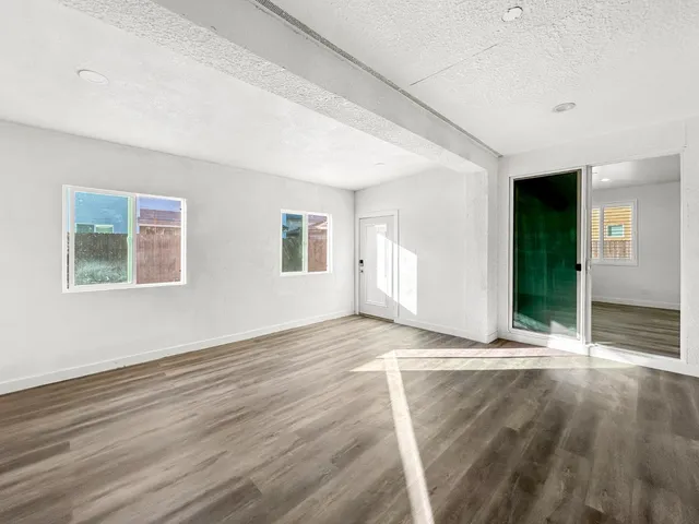 a view of an empty room with wooden floor and windows