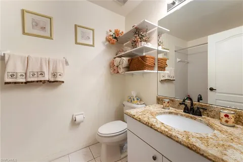 a bathroom with a granite countertop sink a toilet and mirror