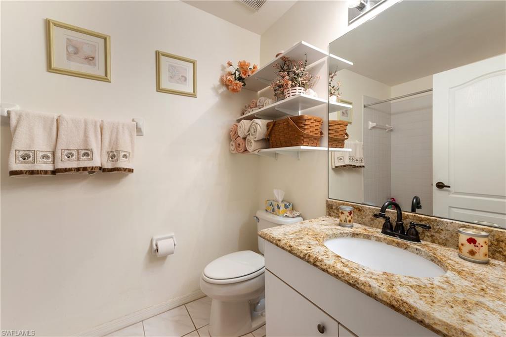 9300 Highland Woods Boulevard, Unit 3206 Bonita Springs, FL 34135 - Photo 11 of 25 a bathroom with a granite countertop sink a toilet and mirror