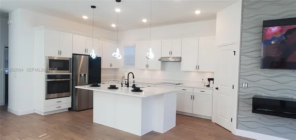 a kitchen with stainless steel appliances kitchen island granite countertop a sink and refrigerator