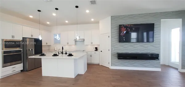 a kitchen with stainless steel appliances kitchen island granite countertop a stove top oven a sink and a refrigerator