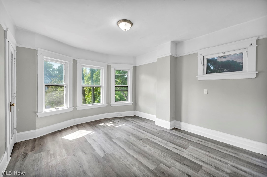 1659 Lee Road Cleveland, OH 44118 - Photo 12 of 46 Light gray walls with white trim, wood-finish flooring, a three-panel bay window, and a flush mount ceiling light