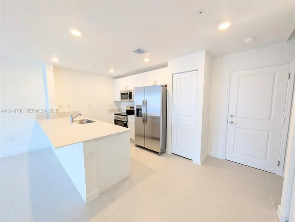 a large kitchen with a sink and refrigerator