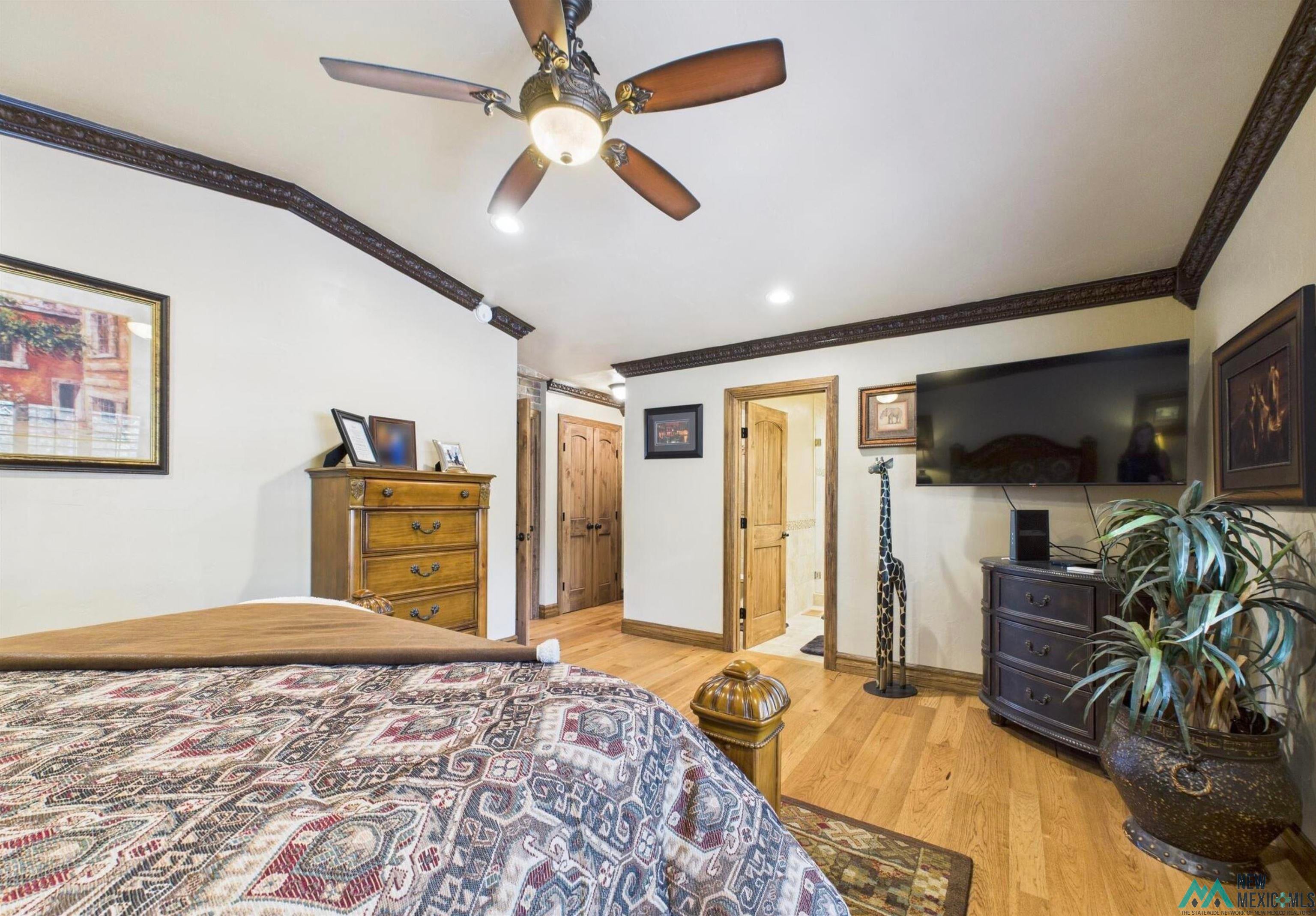 103 Granite Drive Ruidoso, NM 88345 - Photo 14 of 28 Spacious room featuring wood-finish flooring, an ornate ceiling fan with integrated lighting, and decorative crown molding