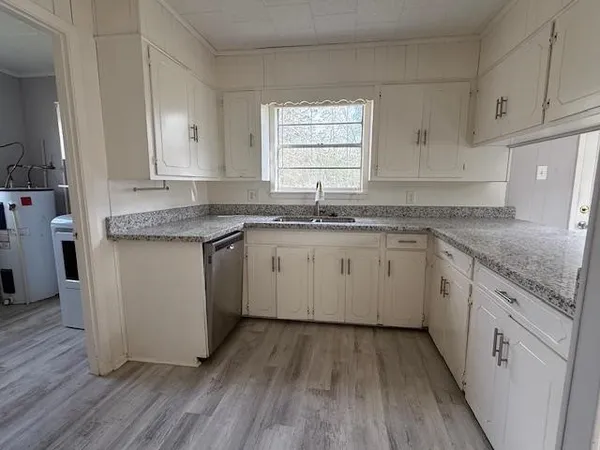 a kitchen with a sink stove cabinets and wooden floor