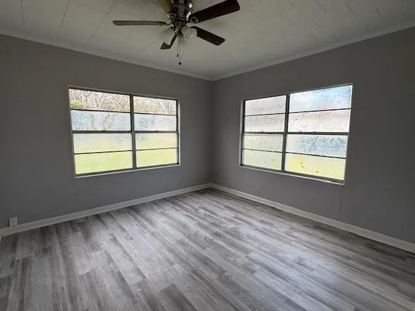 a view of an empty room with wooden floor and a window