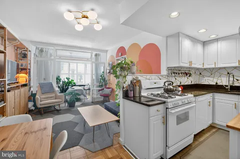 a open kitchen with stainless steel appliances granite countertop a stove a sink dishwasher and white cabinets with wooden floor