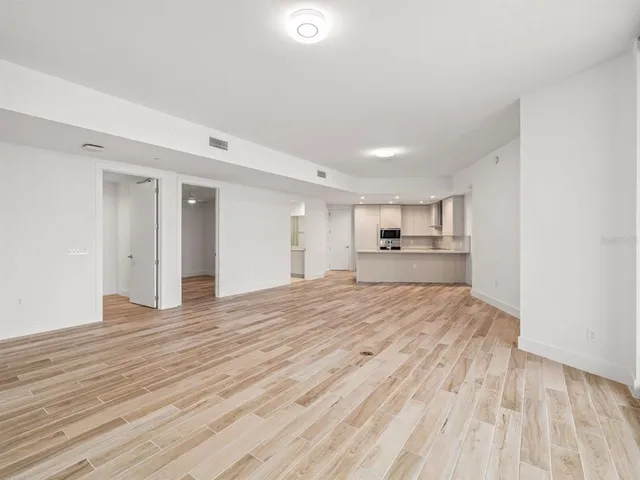a big room with wooden floor and kitchen view