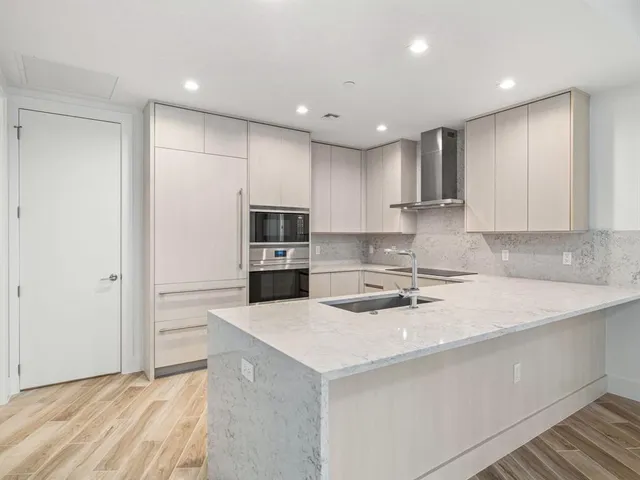 a kitchen with a sink a stove a refrigerator and white cabinets