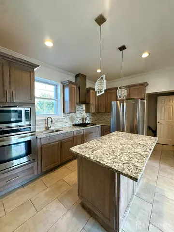 a kitchen with stainless steel appliances kitchen island granite countertop wooden cabinets and granite counter tops