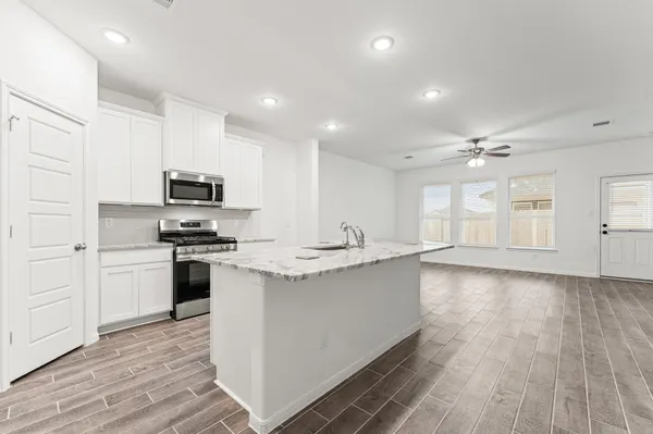 a large kitchen with stainless steel appliances granite countertop a stove a sink dishwasher and a refrigerator with wooden floor