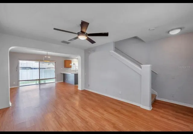 a view of empty room with wooden floor and fan