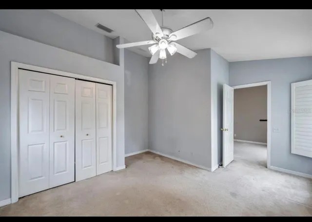 a view of an empty room and chandelier fan