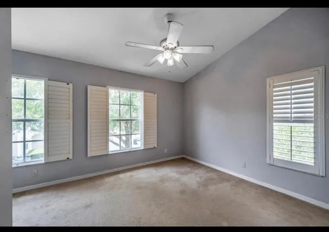 a view of an empty room with chandelier fan and fire place