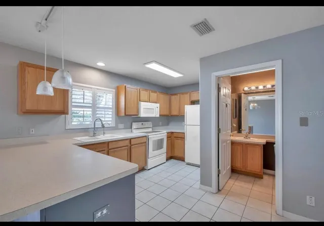 a large kitchen with a large counter top sink and stainless steel appliances