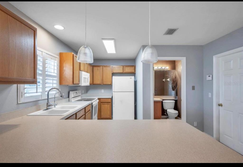 13059 Thoroughbred Loop Largo, FL 33773 - Photo 9 of 32 a kitchen with stainless steel appliances kitchen island granite countertop a sink refrigerator and cabinets