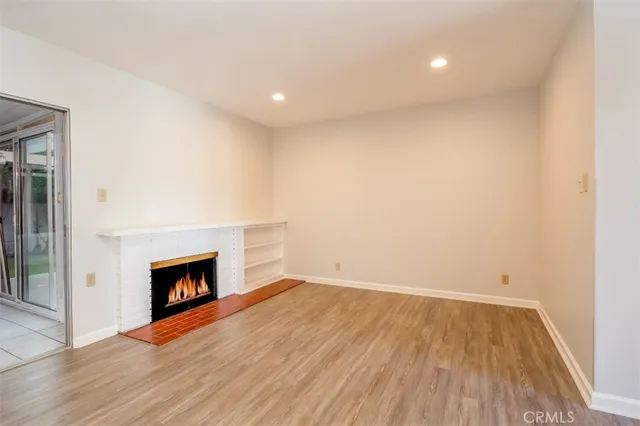 an empty room with wooden floor and fireplace