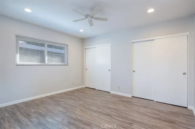 an empty room with wooden floor and a ceiling fan