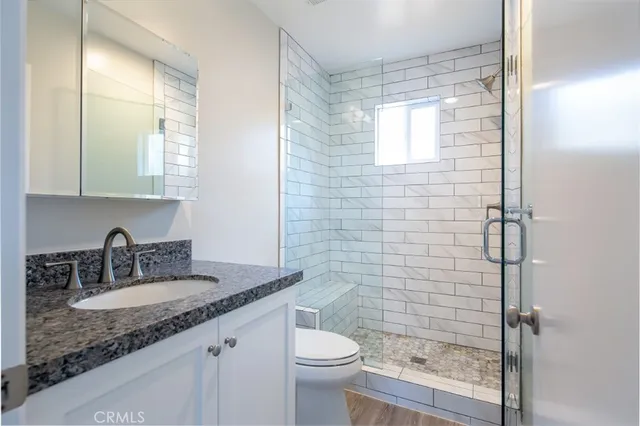 a bathroom with a granite countertop sink toilet and shower