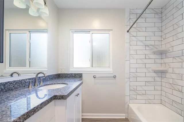 a bathroom with a granite countertop sink a mirror and a bathtub