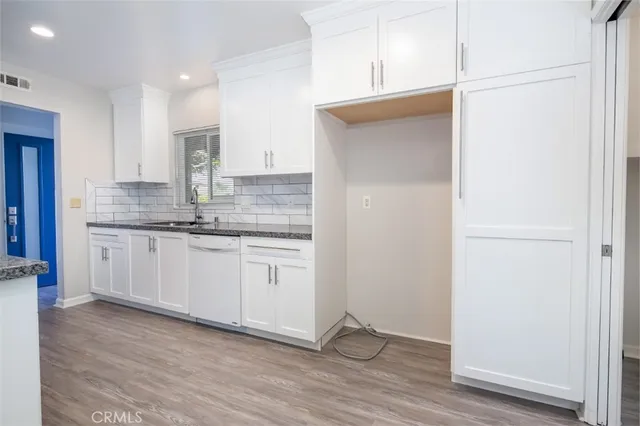 a kitchen with granite countertop white cabinets and white appliances