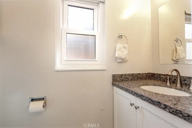 a bathroom with a granite countertop sink and mirror next to a window
