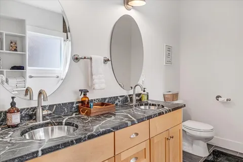a bathroom with a granite countertop sink mirror vanity and toilet
