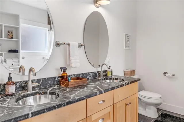 a bathroom with a granite countertop sink mirror vanity and toilet