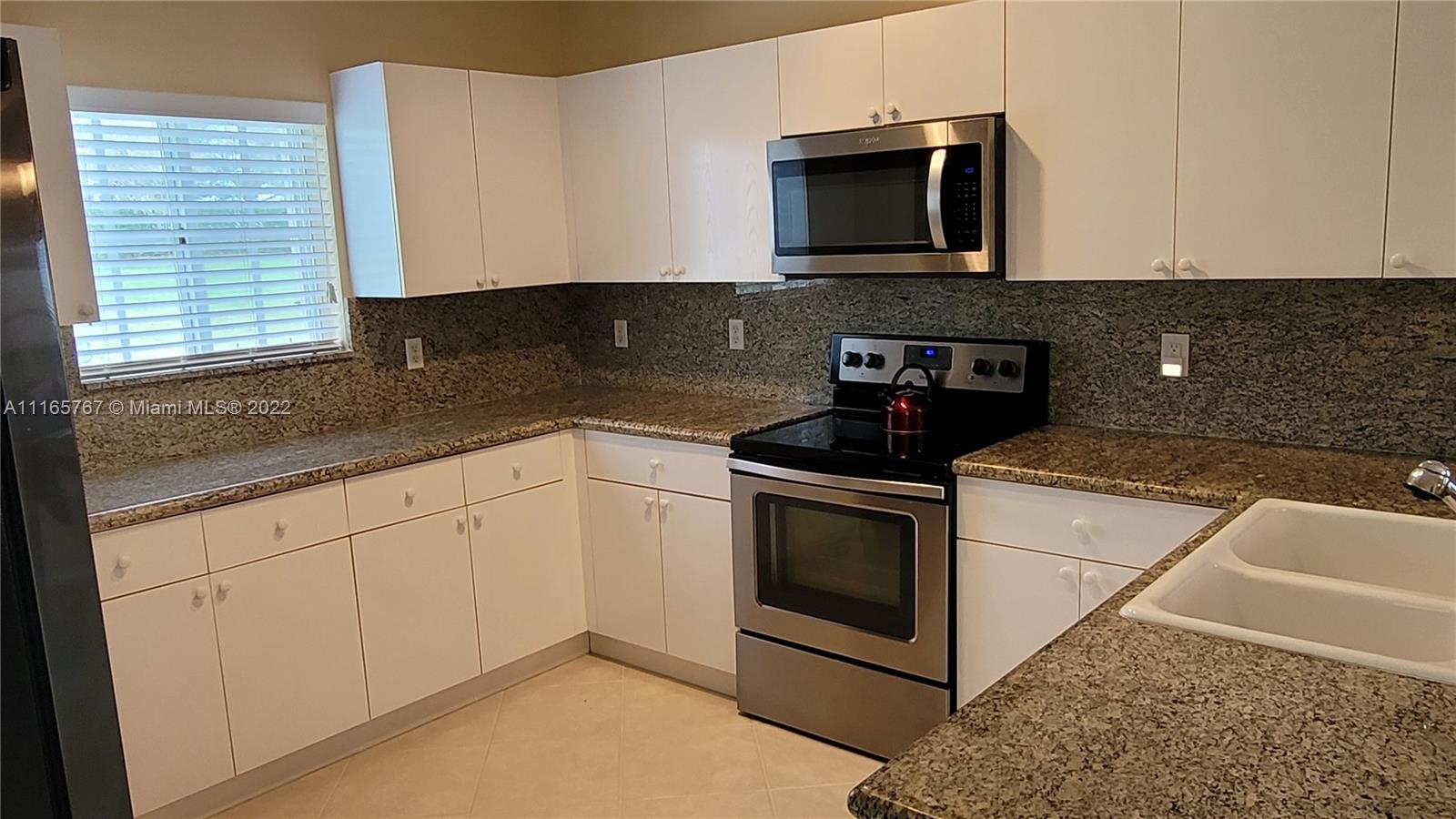 Baywinds West Palm Beach, FL 33411 - Photo 16 of 38 a kitchen with granite countertop white cabinets stainless steel appliances and a sink