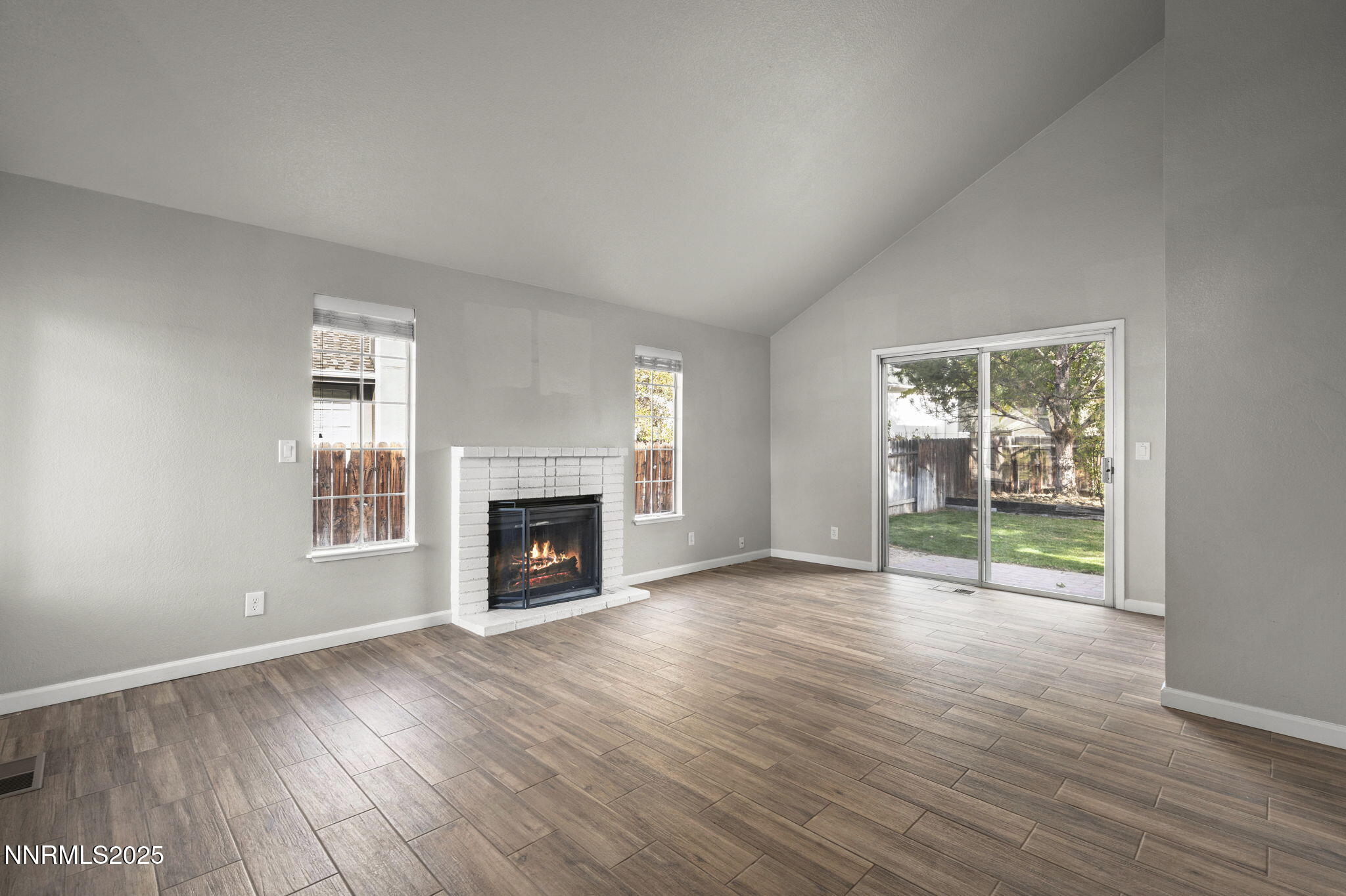 2768 Azuza Way Reno, NV 89502 - Photo 6 of 26 an empty room with wooden floor fireplace and windows