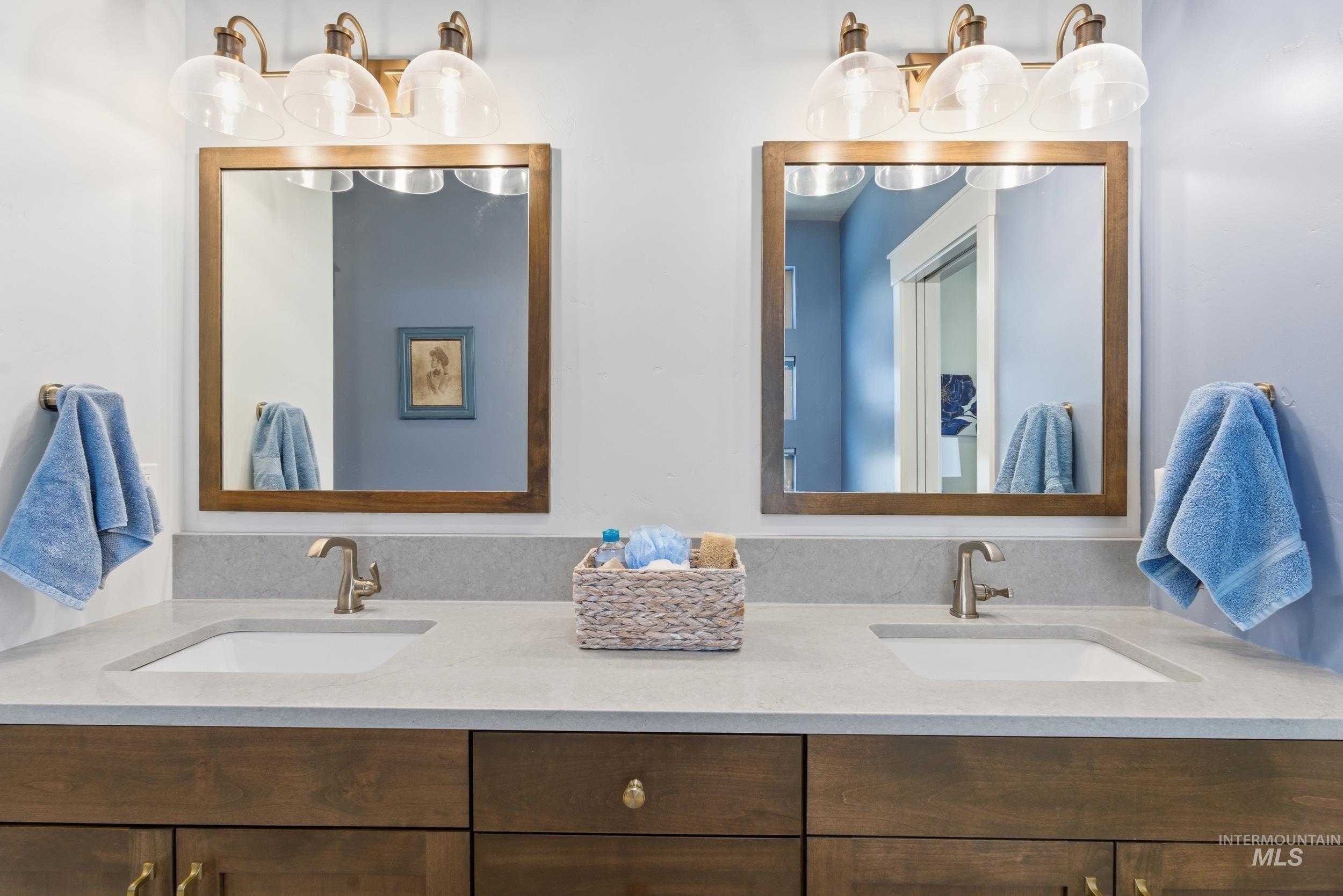 6347 South Utmost Lane Meridian, ID 83642 - Photo 23 of 37 Double vanity featuring two integrated sinks set in a light-toned countertop, wood-finish cabinetry, and individual framed mirrors