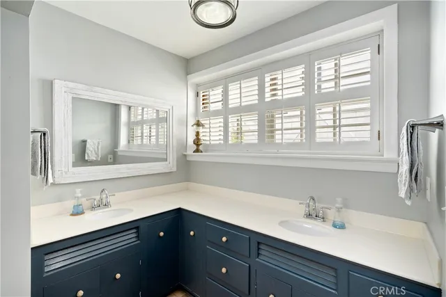 a bathroom with double vanity sink a mirror a window and vanity