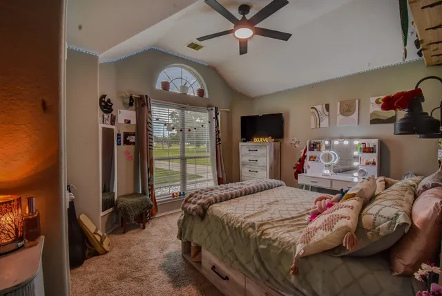 a bedroom with a bed a ceiling fan and a large window