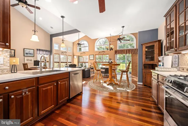 a open kitchen with stainless steel appliances granite countertop a stove top oven a dining table and chairs with wooden floor