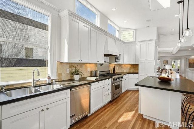 a kitchen with kitchen island granite countertop a sink a stove and a wooden floors
