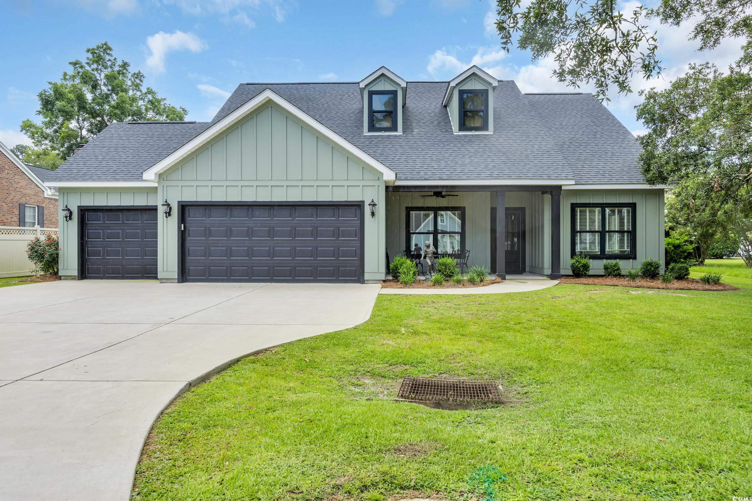 1121 Grimes Street Georgetown, SC 29440 - Photo 2 of 27 View of front of property featuring board and batten siding, a shingled roof, a front lawn, and a garage