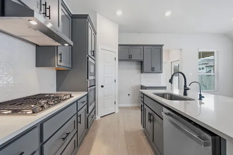 a kitchen with stainless steel appliances granite countertop a sink stove and cabinets