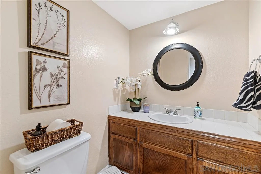 5673 Raintree Way Oceanside, CA 92057 - Photo 4 of 23 a bathroom with a toilet a sink and a mirror
