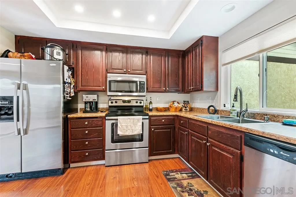 5673 Raintree Way Oceanside, CA 92057 - Photo 5 of 23 a kitchen with stainless steel appliances kitchen island granite countertop a refrigerator stove and sink