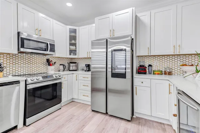 a kitchen with stainless steel appliances granite countertop a refrigerator sink and white cabinets