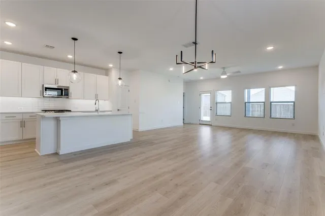 a view of a kitchen with kitchen island a sink wooden floor and stainless steel appliances