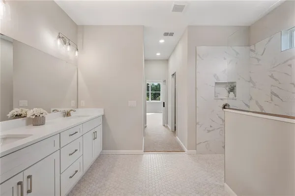 a spacious bathroom with a double vanity sink a mirror and shower