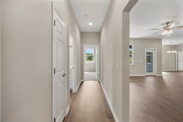 a view of a hallway with wooden floor and a bathroom