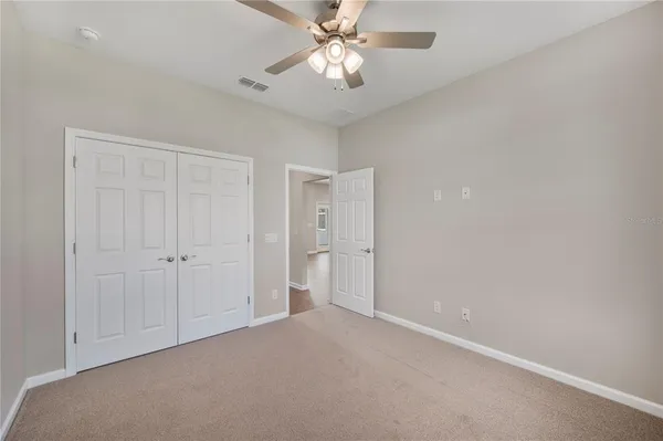 a view of an empty room and chandelier fan