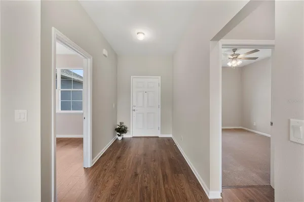 a view of a hallway with wooden floor and a bathroom