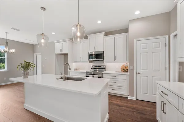 a kitchen with kitchen island a white counter top space cabinets and stainless steel appliances